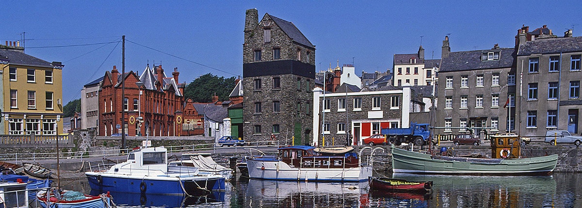small boats are docked at a pier with brown stone buildings 